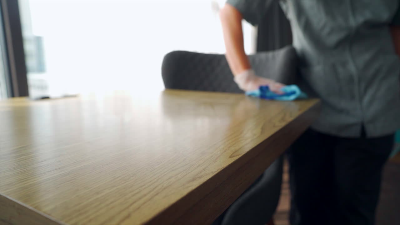 The maid efficiently goes about her tasks, tidying up the hotel room with precision and care, by wiping and cleaning everything in a hotel room