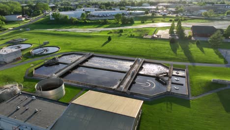 ephrata borough wastewater treatment plant during sunny day with traffic on street in distance. green grass field in area of factory in pa, united states. drone wide shot.