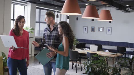 Diverse-male-and-female-colleagues-in-discussion-using-laptop-in-casual-office-meeting,-slow-motion