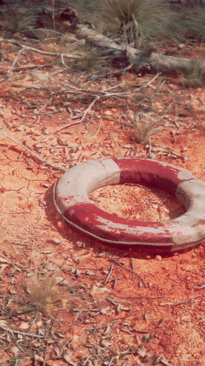 un salvavidas rojo y blanco yace abandonado en la tierra seca y agrietada.