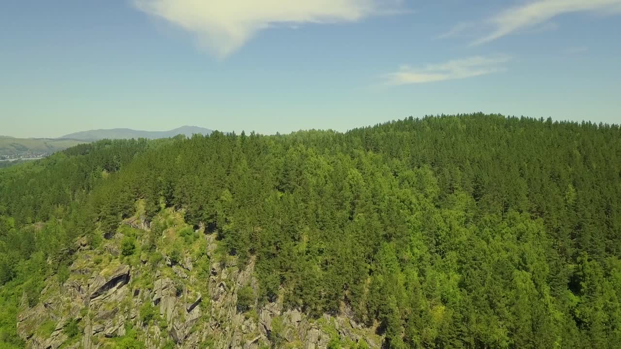aéreo volando sobre una montaña de piedra con bosque mixto