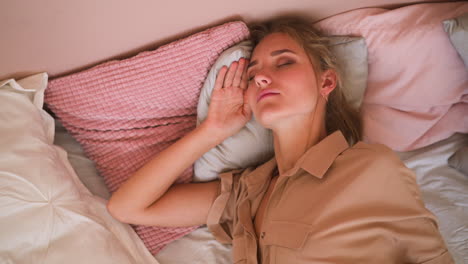 mujer rubia gira en la cama y cubre con almohada por la mañana