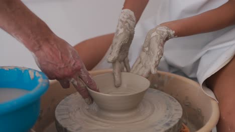 hands molding clay on a pottery wheel