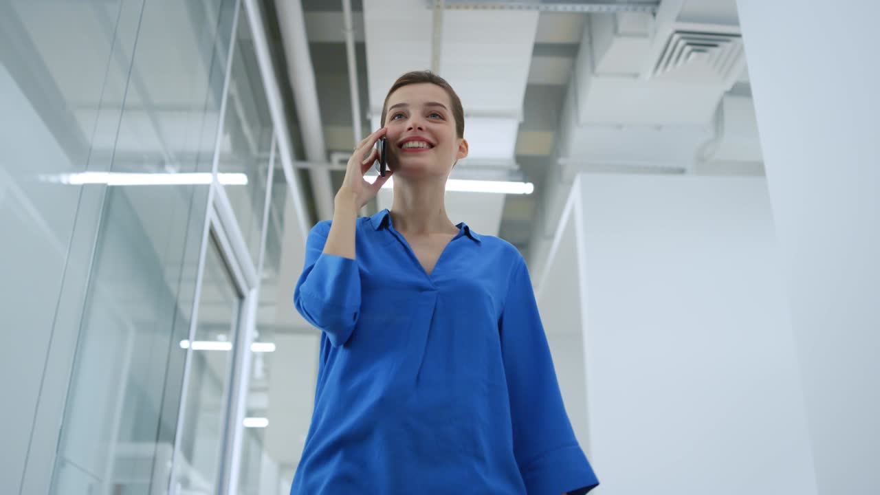 mujer de negocios sonriente usando un teléfono inteligente en una oficina moderna