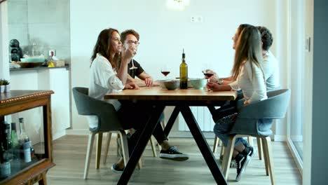 Side-view-of-cheerful-friends-drinking-wine-at-kitchen