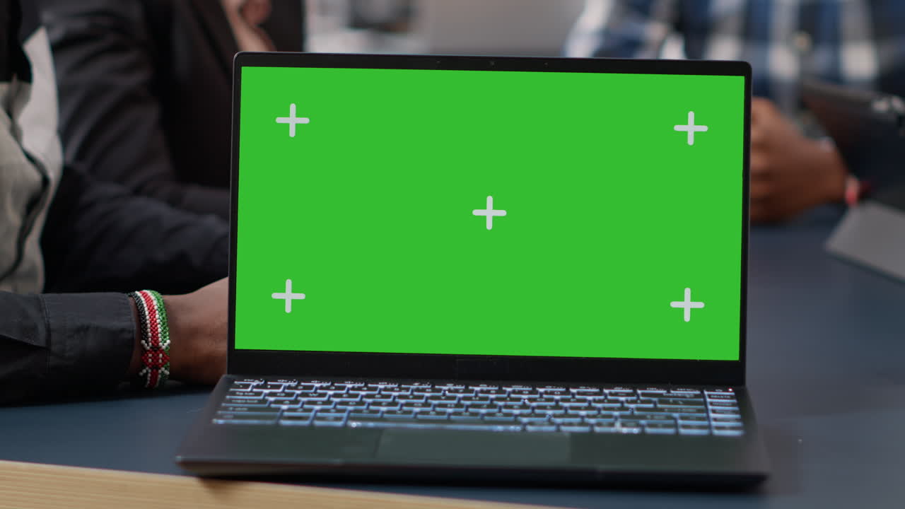 Laptop display with green screen background on office desk