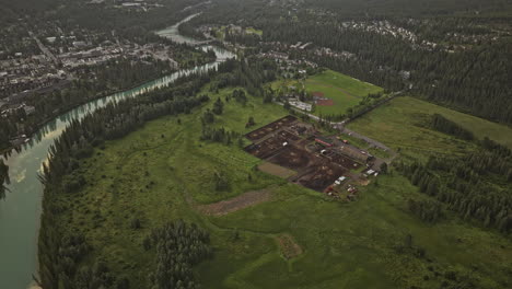 banff ab canada aerial v14 drone flyover stables capturing bow river, picturesque townscape, forested valley and sun peeking through behind the mountain ranges - shot with mavic 3 pro cine - july 2023