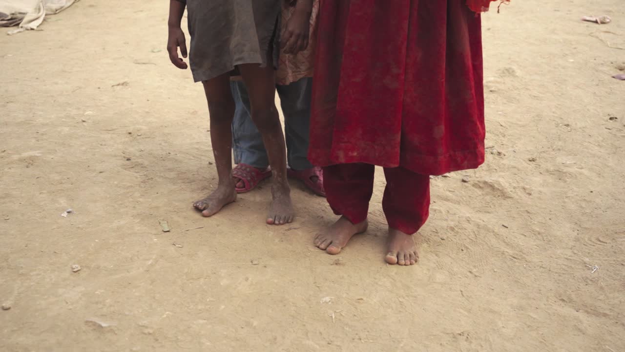 The children from a poor village are shoeless and dressed in torn clothing.