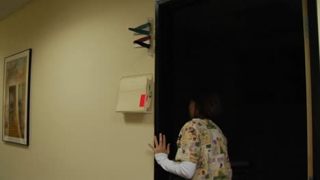 a medical professional places paperwork into a container outside a room