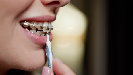 mujer limpiando los dientes con aparatos ortopédicos usando un cepillo interdental
