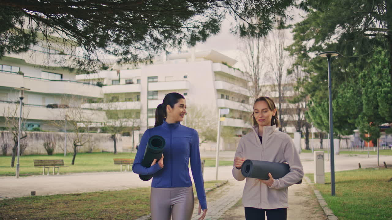 amigos de yoga comunicándose en el callejón del parque. mujeres sonrientes cruzando en la naturaleza de primavera.