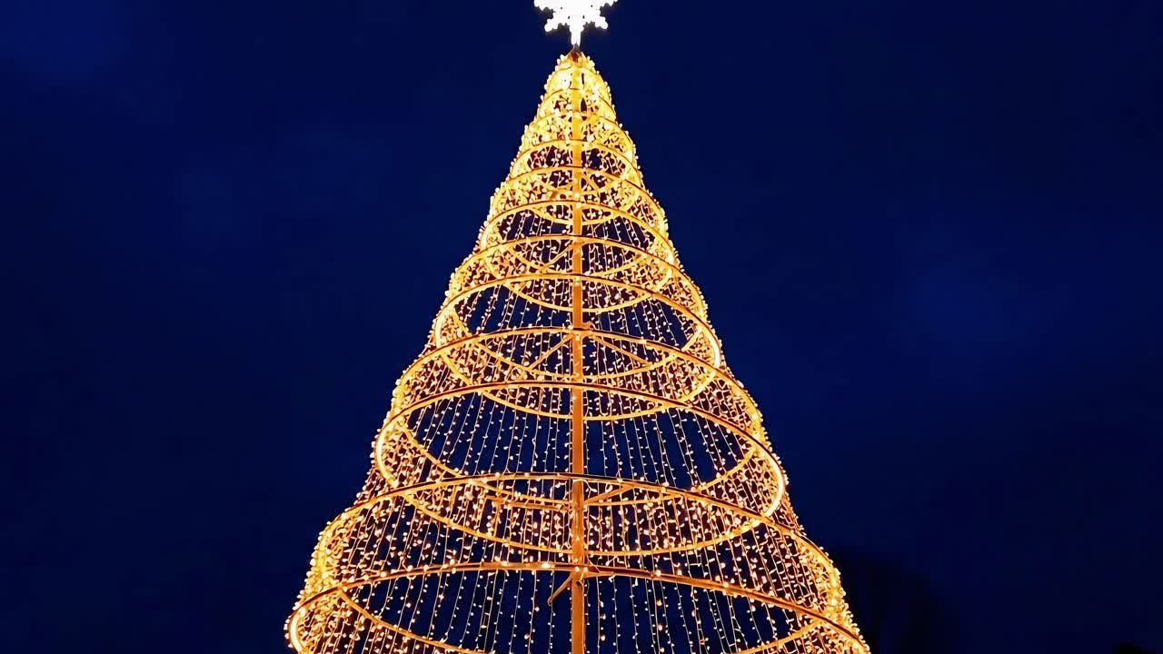 Upward angle of a glowing spiral Christmas tree at night, perfect for festive video