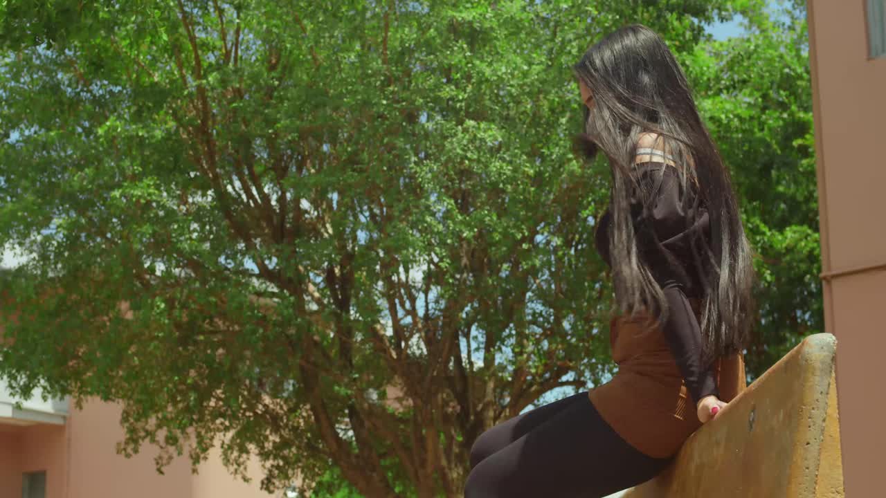 Joven hispana en un parque con una minifalda marrón.