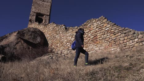 a girl in winter clothes walking next to a fort as part of an archeological landscape