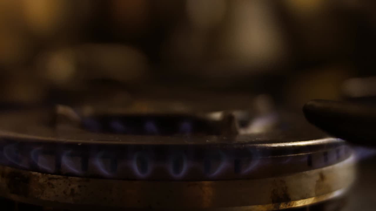 Turning on the cooktop gas cooker on black background. Kitchen burner turning on. Close up on the flame. Natural gas inflammation in stove burner, close up view. Gas burning from a kitchen gas stove