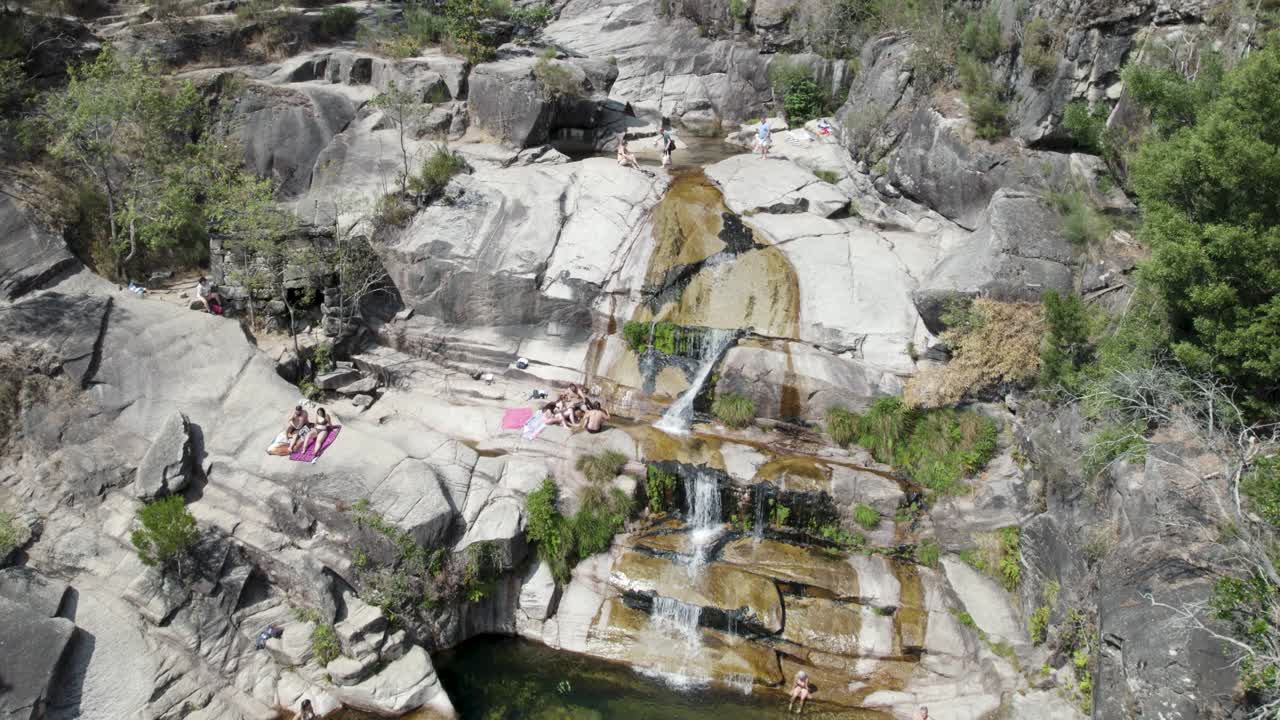antena de arriba hacia abajo sobre personas tomando el sol sobre rocas, en cascada fecha de barjas