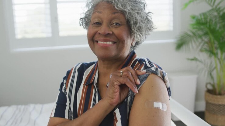 Smiling african american senior woman showing plaster after vaccination