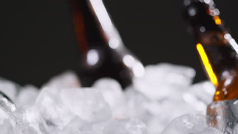 primer plano de una persona que toma una botella de vidrio refrigerada de cerveza fría o bebidas gaseosas de un cubo lleno de hielo contra un fondo negro 1