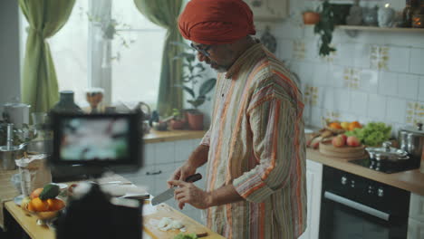 indian culinary blogger chopping onion in front of camera in kitchen