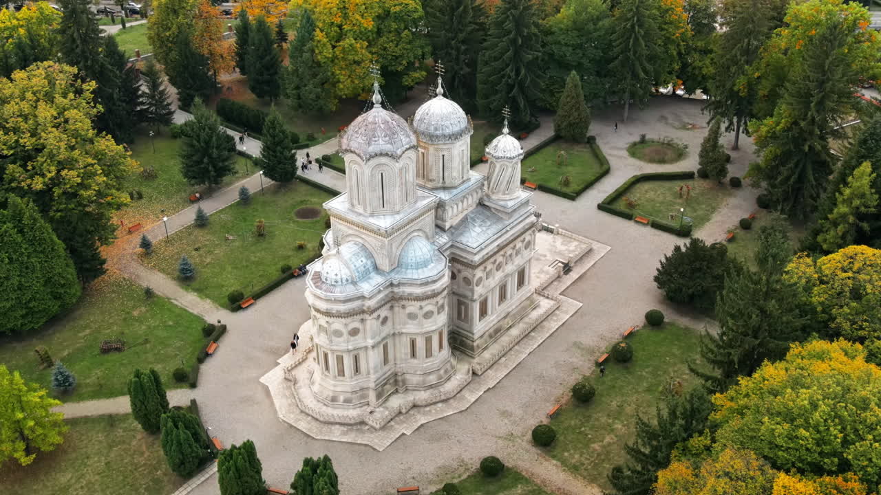 Aerial drone view of The Cathedral of Curtea de Arges, Romania. Square with greenery and people
