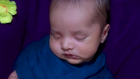 lindo bebé recién nacido durmiendo en una envoltura de bebé con flores en un estilo único desde el ángulo superior