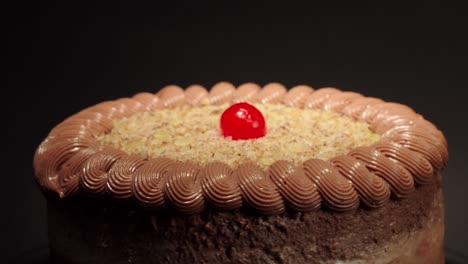 close up detail shot mocha cake in a turn table with black background mocca moka mochachino with shiny cherry on top fresh delicious tasty dessert party celebration