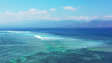 hermosas olas blancas que hacen espuma sobre la laguna turquesa, salpicando arrecifes de coral, cielo azul brillante con nubes blancas en bali