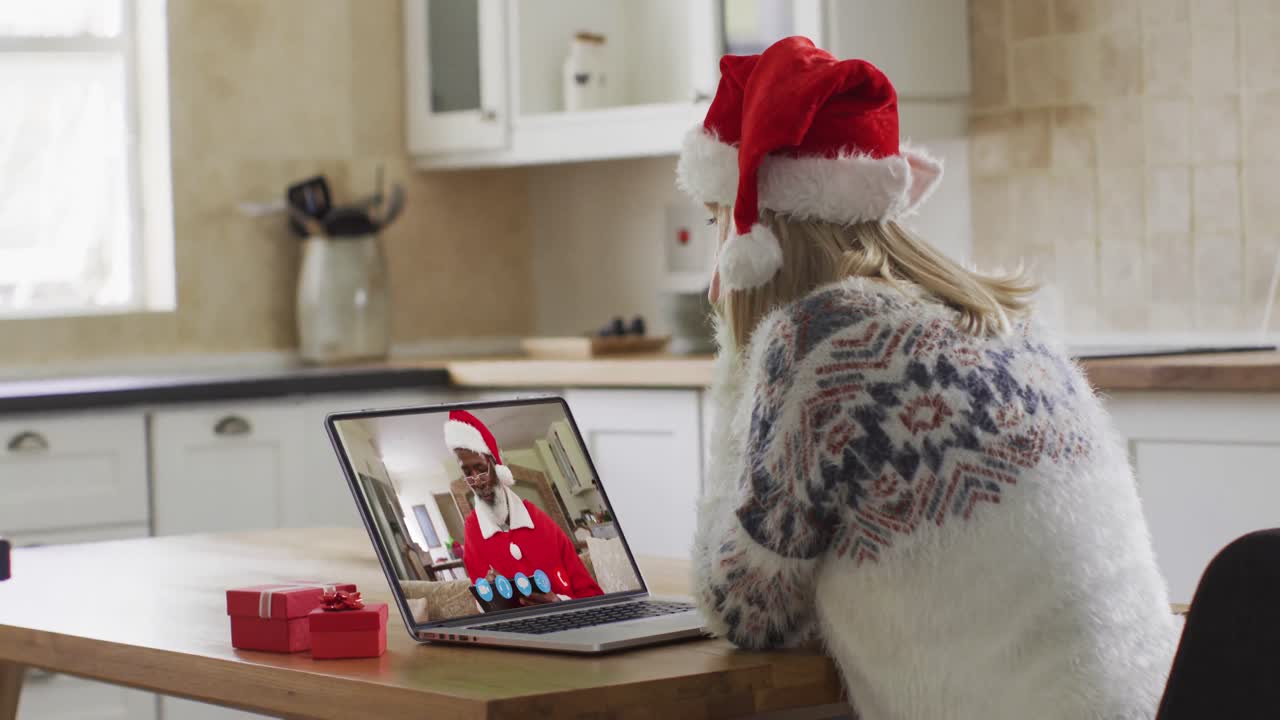 mujer caucásica con sombrero de papá noel en una videochat portátil durante la navidad en casa