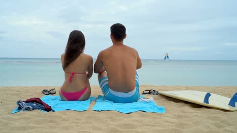 una joven pareja sentada en la playa 4k