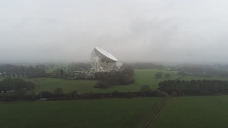 aerial jodrell bank observatory lovell telescope slow descend across misty rural countryside