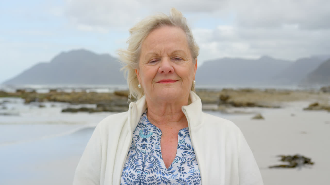Front view of old caucasian senior woman standing at beach 4k