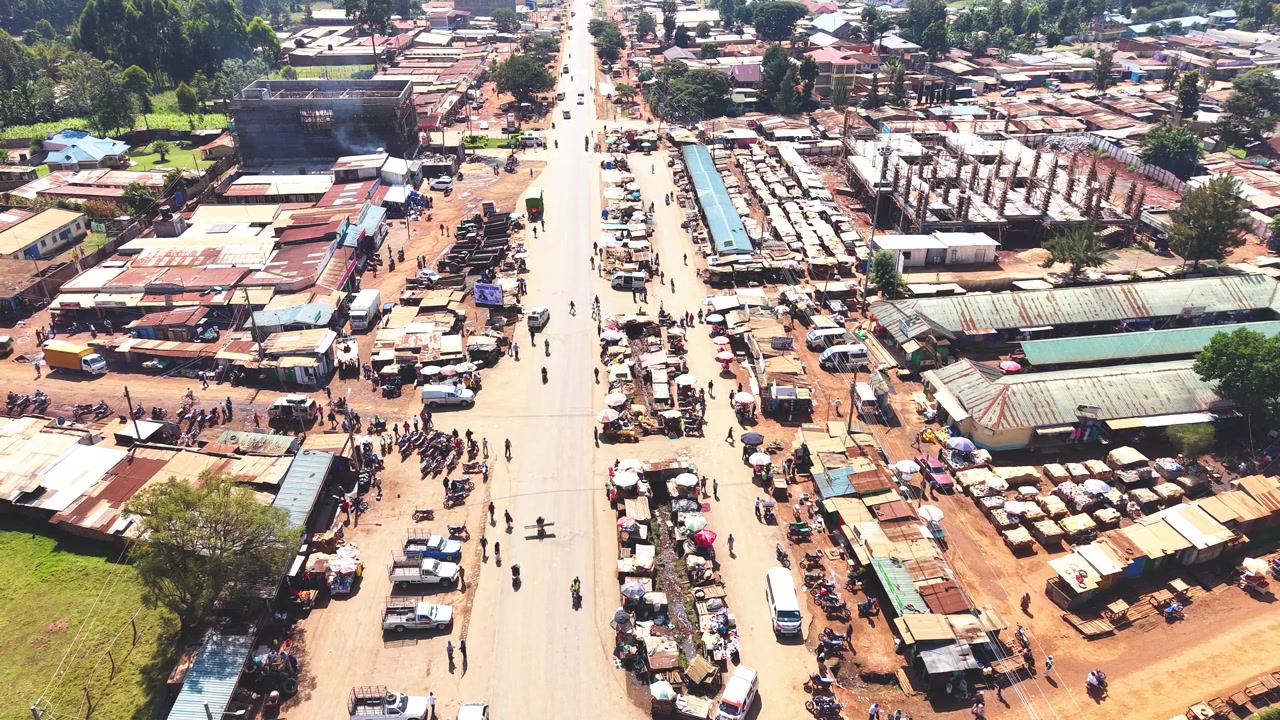Ampia ripresa aerea che mostra lo skyline moderno di un insediamento rurale del Kenya con architetture antiche sullo sfondo e il povero distretto di baraccopoli di Kibera in primo piano