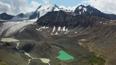 wide aerial drone shot of the surrounding land around the ala-kol lake and glacier in kyrgyzstan