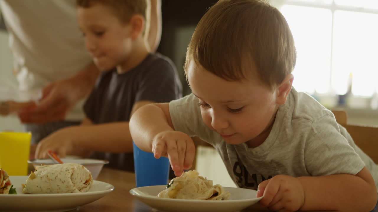 Bambini che mangiano con il padre al tavolo da pranzo 4k