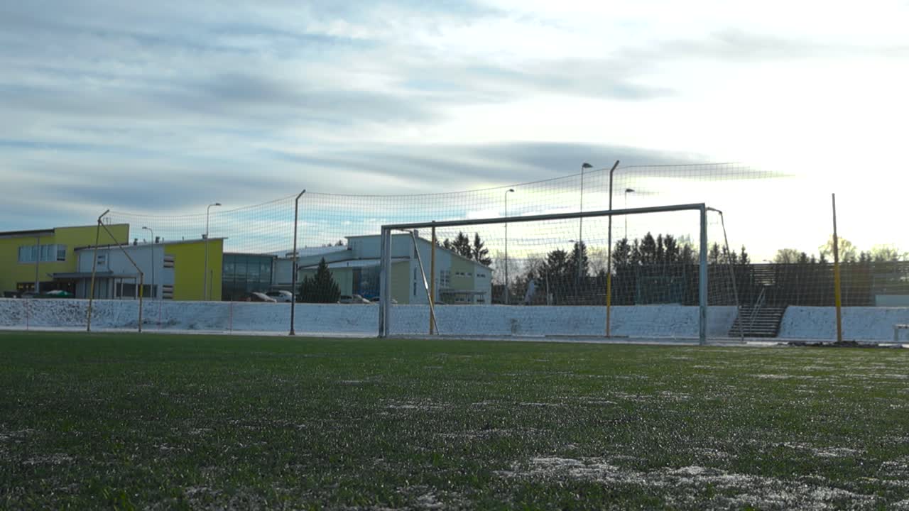 imágenes de bajo ángulo de un estadio de fútbol o un estadio de fútbol con hierba verde durante el invierno en los terrenos de la escuela de laagri estonia. la hierba está ligeramente cubierta de nieve y un gol de fútbol está en la parte de atrás
