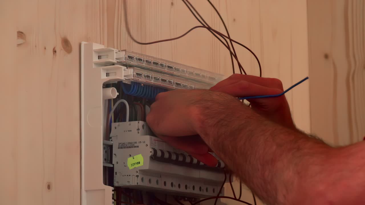 Electrician installing network cables in home distribution panel setup process