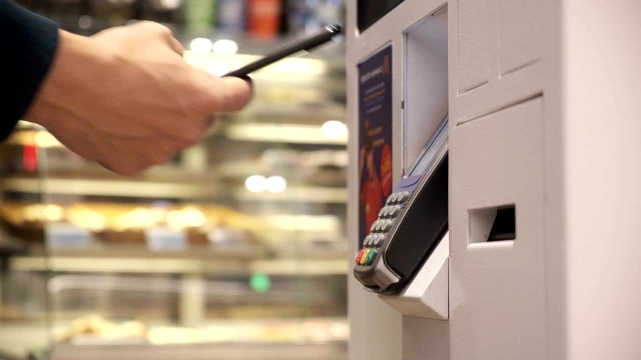 a young man buys a telephone in a contactless way in a self-service machine. men pay by phone. close up. 4k Video