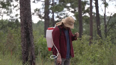 Mittlere-Aufnahme-Eines-Försters,-Der-Mit-Einer-Rucksackspritze-Im-Wald-Arbeitet.-Er-Trägt-Ein-Rotes-Hemd-Und-Einen-Hut