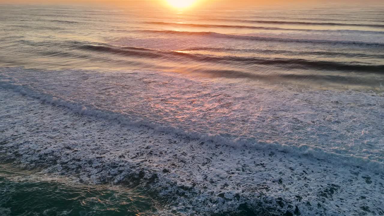 A serene sunrise casts golden hues over the Pacific Ocean waves at Gold Coast, Australia, creating a tranquil and picturesque scene