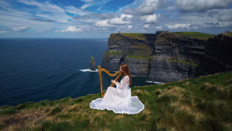 woman playing harp on dramatic cliffs overlooking the ocean