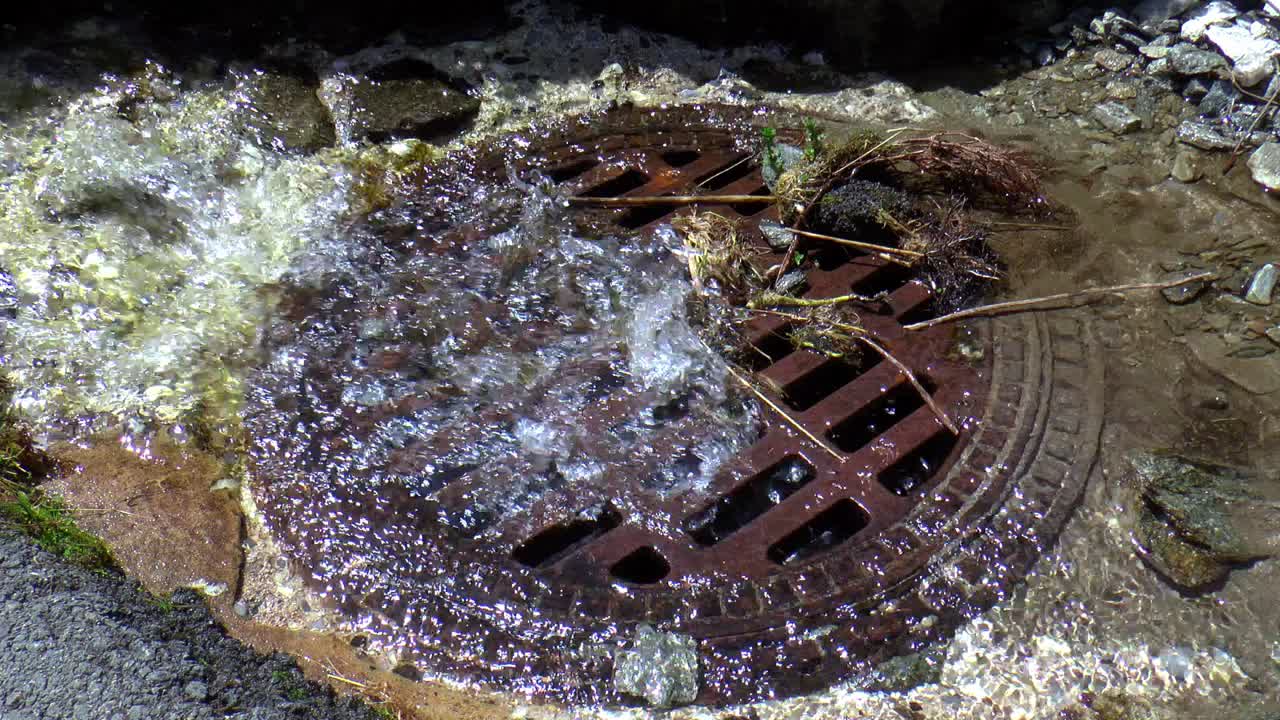 많은 양의 빗물이 배수구에서 빠르게 흐른다.