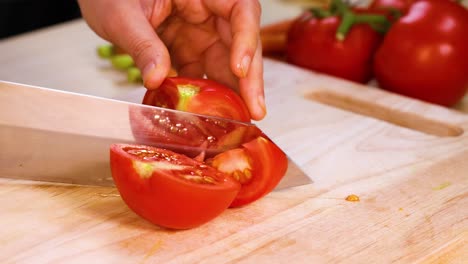 slicing tomatoes with a knife on wooden board