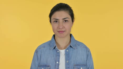 young indian woman smiling at camera, yellow background
