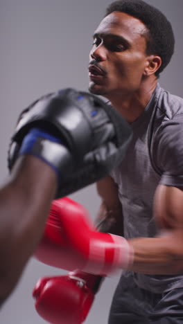 Vertical-Video-Studio-Shot-Of-Male-Boxer-Sparring-Working-Out-With-Trainer-Wearing-Punch-Mitts-Or-Gloves-Practising-For-Fight-6