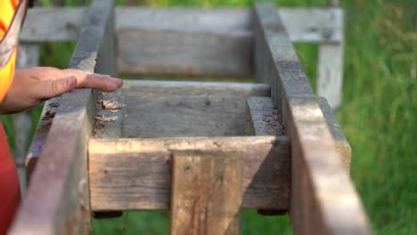 Ein-Mann-Im-Orangefarbenen-Hemd-Stützt-Mit-Einer-Zugrasur-Ein-Brett-Ab,-Das-Auf-Einer-Selbstgebauten-Holzfräsanlage-Verwendet-Wird