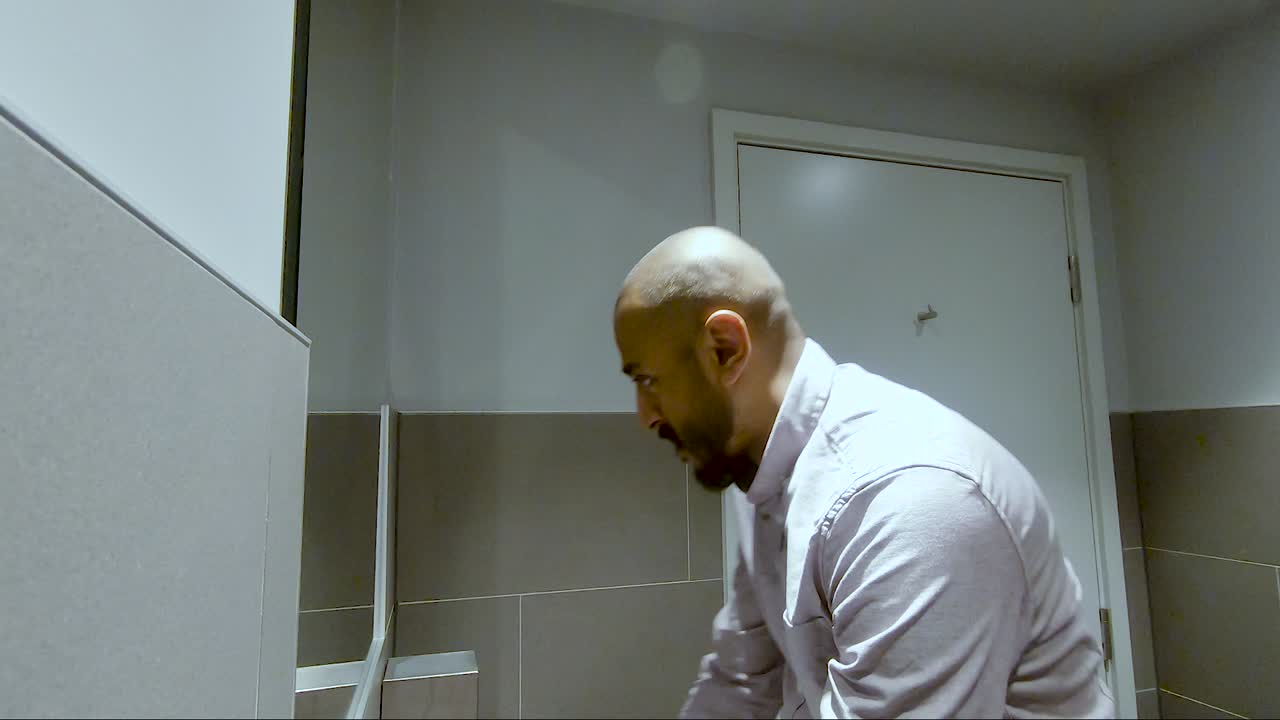 hombre indio asiático entrando al baño, luciendo angustiado