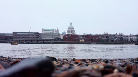 low shot of snow falling from thames river bank towards st pauls cathedral london