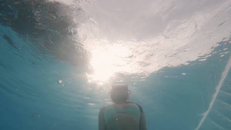 Beautiful-Girl-in-Swimsuit-Underwater-with-Vintage-Diving-Goggles-Surfacing