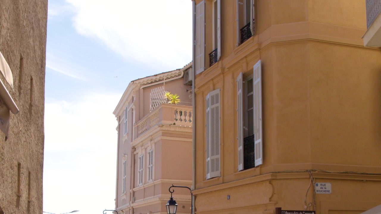 Plano estático em ângulo baixo de edifícios amarelos com persianas sob um céu azul brilhante.