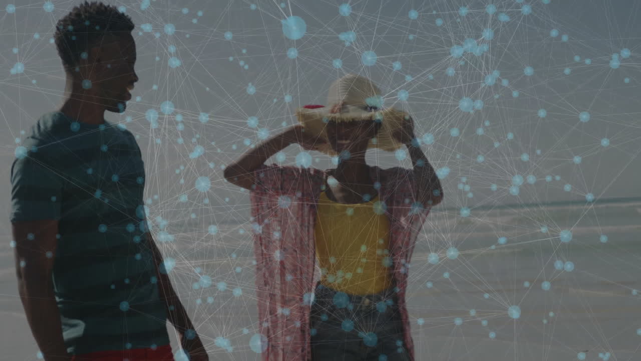 Man standing with woman at beach, adjusting straw hat under digital technology network overlay
